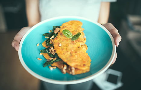 person holding round ceramic plate with dish on top thumbnail