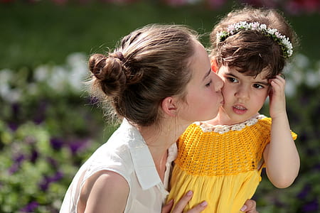 selective focus photography of woman kissing girl's cheeks thumbnail