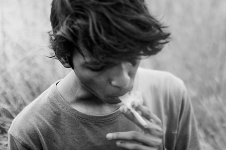gray scale photo of man smoking cigarette thumbnail