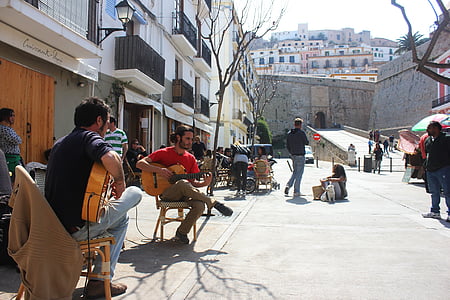 man wearing red shirt playing guitar on street during daytime thumbnail