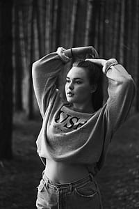 greyscale photo of woman standing near trees thumbnail
