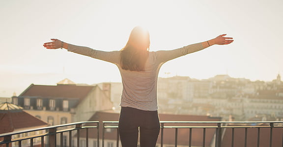 woman in grey long-sleeved shirt standing in front of concrete houses during daytime thumbnail