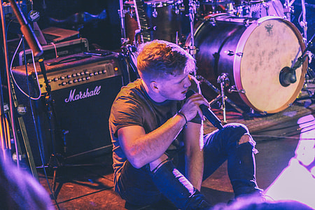 man sitting on stage holding microphone thumbnail