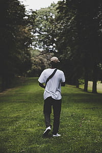 man walking on lawn surrounded by trees thumbnail