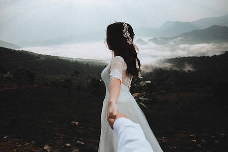 person holding woman's hand looking towards foggy mountain thumbnail