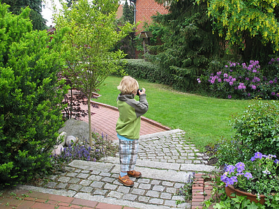 boy standing on brick pathway using camera thumbnail
