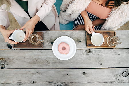two women standing in front of table holding white teacups thumbnail