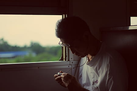 man using earphones sitting inside vehicle near window thumbnail