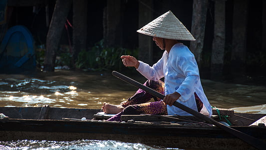 man wearing white long-sleeved shirt sitting on brown wooden boat holding paddle thumbnail