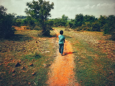 boy walking on grass during daytime thumbnail