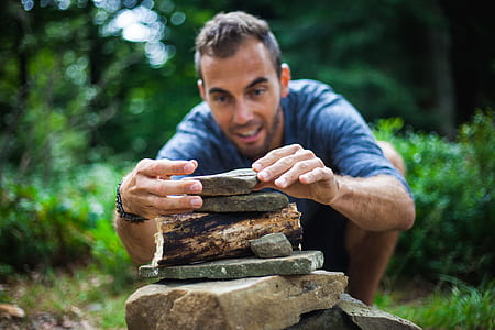 selective focus photography of man piling stones at daytime thumbnail