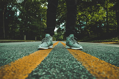 person wearing pair of gray shoes standing on yellow lane road thumbnail