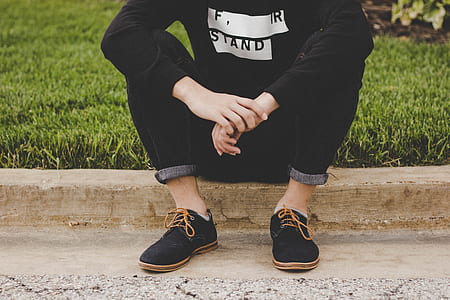 person sitting on concrete road beside grass of field thumbnail
