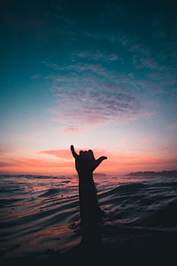 silhouette photography of person's hand above water thumbnail