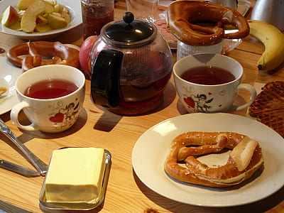 baked bread on white ceramic plate beside butter and cup of tea thumbnail
