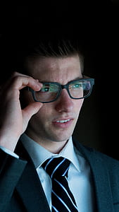 man in black blazer holding his black framed eyeglasses thumbnail