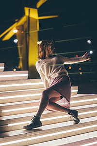woman in white knit long-sleeved top standing on white stair during nighttime thumbnail