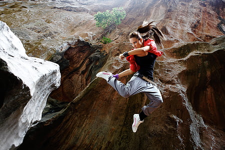 woman in black shirt jumping at the mountain thumbnail