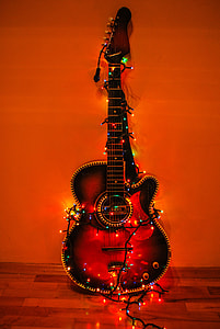acoustic guitar surrounded with string lights against the wall thumbnail