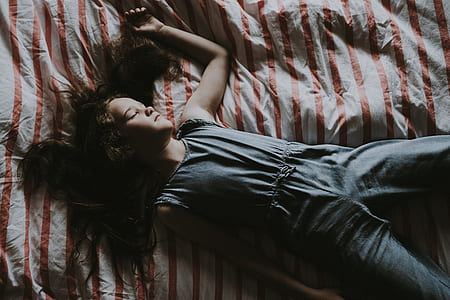 woman wearing gray sleeveless jumpsuit lying on bed thumbnail