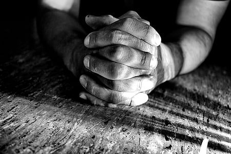 person holding both hands while leaning on surface greyscale photography thumbnail