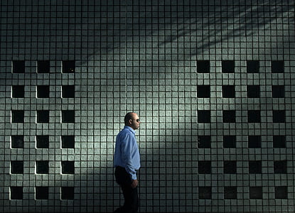 man walking beside white and gray wall thumbnail