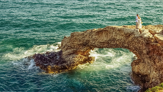man and woman on top of rock formation thumbnail
