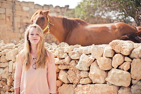 A teenage blonde girl wearing peach dress standing outside a horse ranch thumbnail