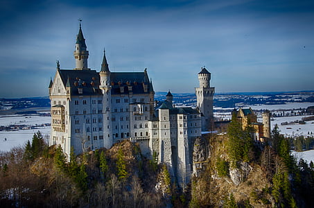 white and black castle surrounded by trees landscape photography thumbnail