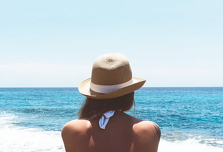 woman in front of body of water wearing brown hat during daytime thumbnail