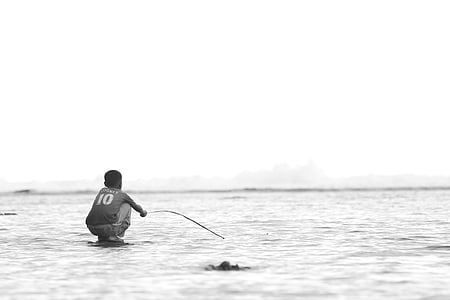 grayscale photo of man wearing shirt near body of water thumbnail