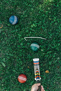three cricket balls with bat on green grass thumbnail