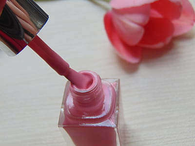 pink nail polish bottle on white wooden surface thumbnail