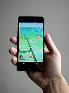 person holding smartphone displaying Pokemon Go application thumbnail