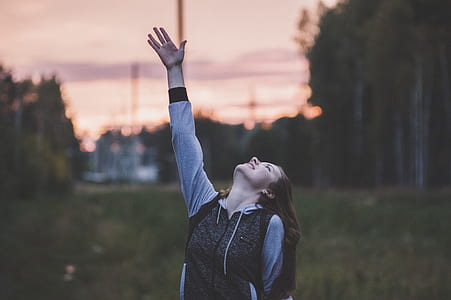 Woman in Gray and Black Zip-up Hoodie Raising Her Right Hand thumbnail
