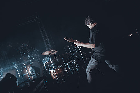 man playing guitar in front drum kit thumbnail