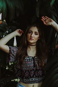 woman wearing crop top with choker beside a plant thumbnail