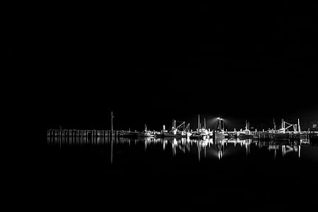 grayscale photo of boats reflecting on body of water thumbnail