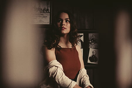 woman sitting near brown wall with framed photos thumbnail
