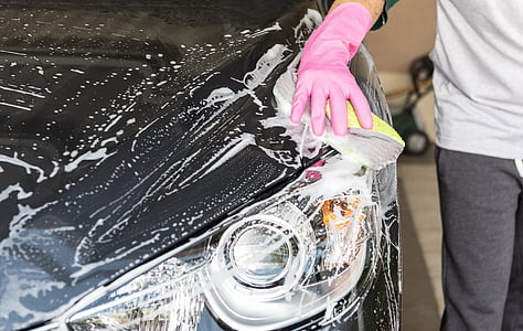 person wearing pink rubber glove washing black car thumbnail