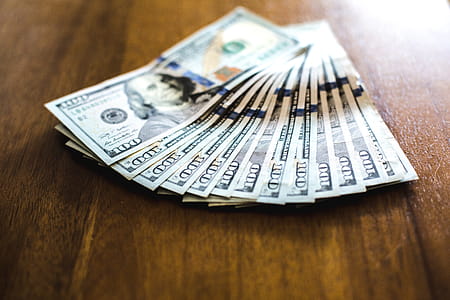 Close up of hundred dollar bills fanned out on wooden surface thumbnail
