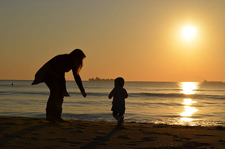 silhouette photo of child running towards mother in seashore thumbnail