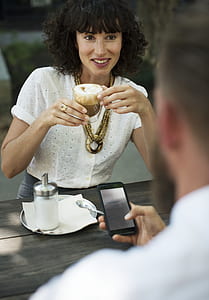 woman holding clear glass cup in front of man holding smartphone thumbnail