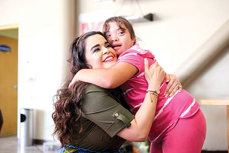woman hugging girl near white wall thumbnail