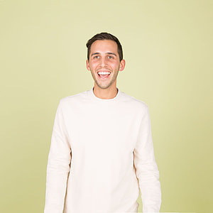 man in white long-sleeved shirt near beige wall thumbnail