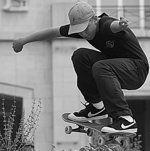 grayscale photo of boy riding skateboard thumbnail