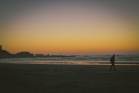 person walking near body of water during sunset thumbnail