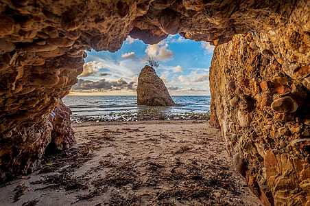 brown rock formation on sea under blue sky during daytime thumbnail