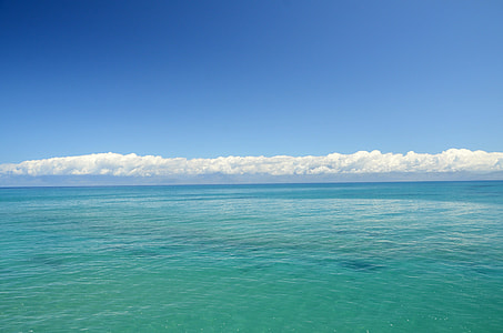 body of water near white clouds during daytime thumbnail