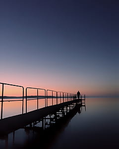 silhouette of person standing on dock thumbnail